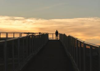 silhouette photography of man standing on corner of bridge by Gabriel courtesy of Unsplash.