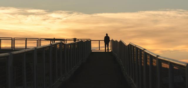 silhouette photography of man standing on corner of bridge by Gabriel courtesy of Unsplash.